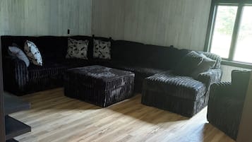 A room with a sectional sofa, ottomans, and a ceiling fan.