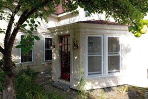 Ein kleines, eingeschossiges Haus mit roter Tür, zwei Fenstern und einem Steinfundament.