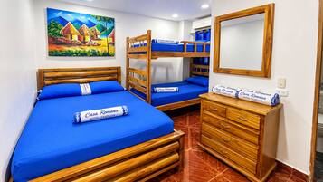 Une chambre d’hôtel avec deux lits superposés, une commode en bois et un tableau au mur.