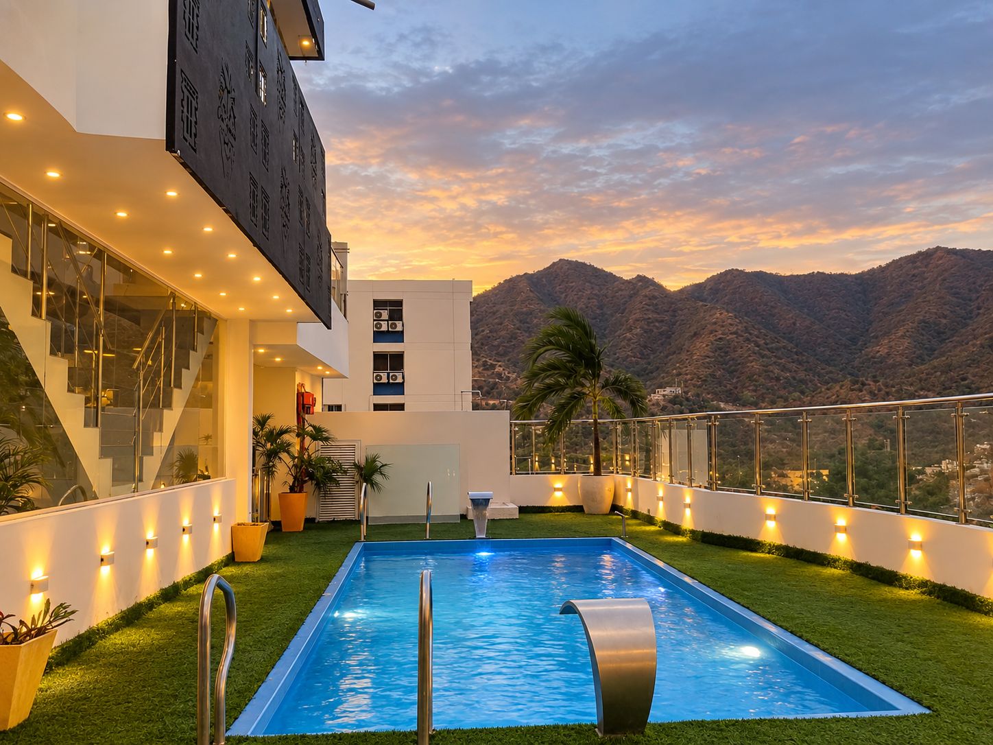 Un bâtiment moderne doté d’une piscine, d’un escalier et offrant une vue sur les montagnes.