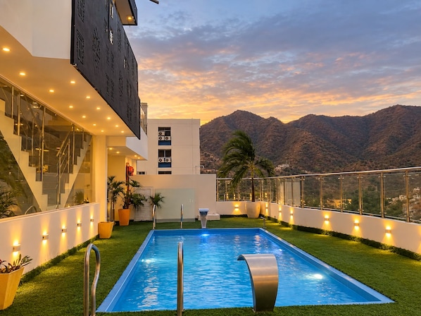 A modern building with a pool, stairs, and a view of mountains.