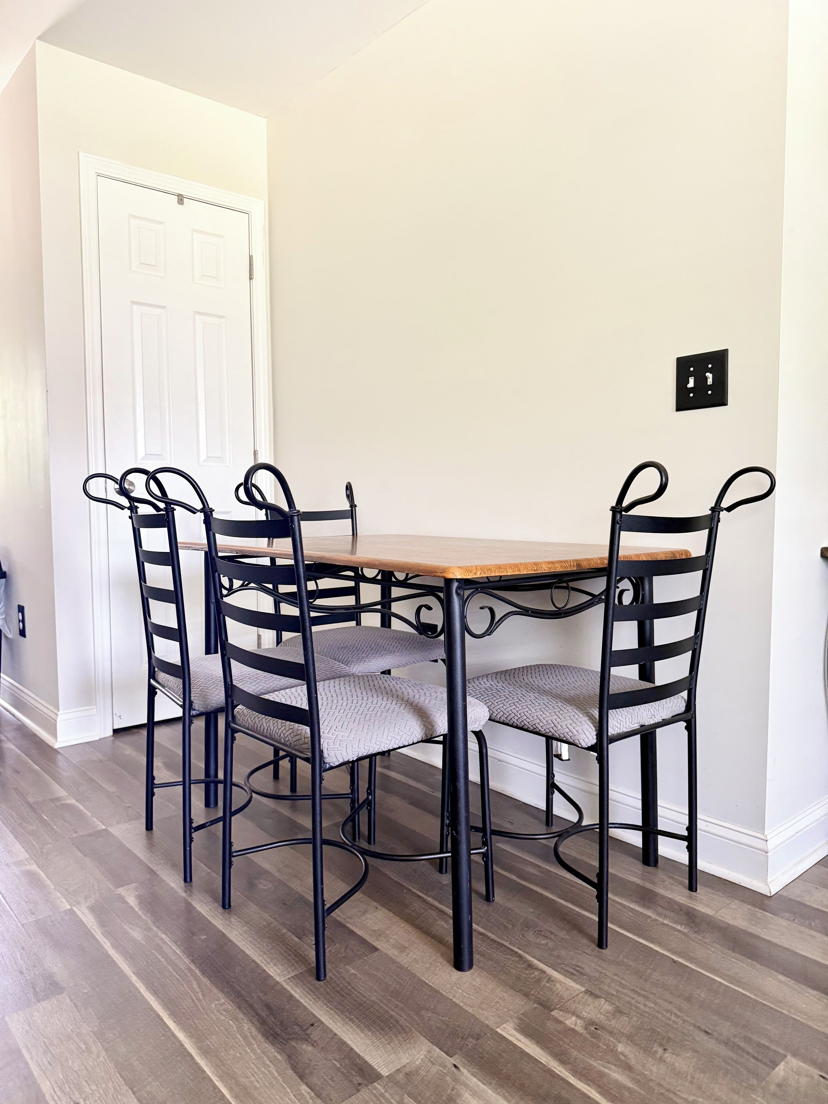 A dining area with a wooden table and four chairs with metal frames and cushioned seats.