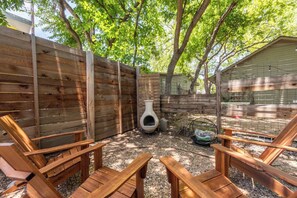 A backyard with a wooden fence, a bird bath, and a grill area. - Urban East Austin Retreat (Austin)