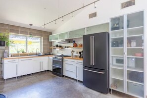 A modern kitchen with white cabinets, a black refrigerator, and a built-in oven. - Urban East Austin Retreat (Austin)