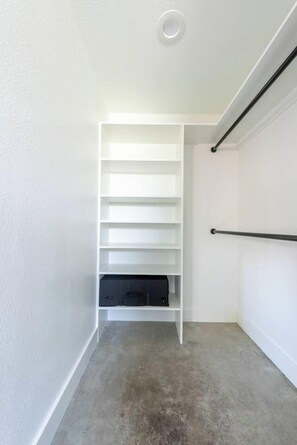 A room with a white closet, a black shelf, and a grey carpet. - Urban East Austin Retreat (Austin)