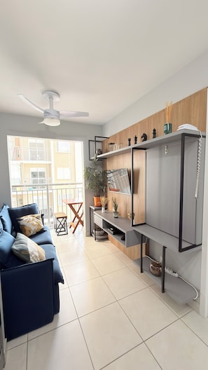 Ein modernes Wohnzimmer mit einer Couch, einem Esstisch und einer Küchenzeile mit Kühlschrank und Schränken.