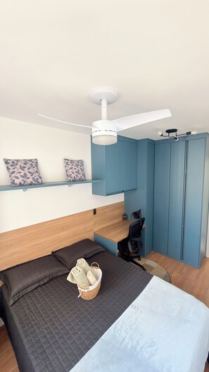 Een moderne slaapkamer met een bed, bureau, stoel, plafondventilator en een kledingkast.