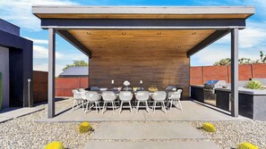 Eine Terrassengruppe mit überdachtem Essbereich, Grill und Sitzgelegenheiten.