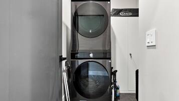 A laundry room with two front-loading washing machines, a wall-mounted dryer, and a GRACO brand sign.
