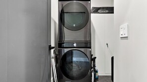 Ein Waschraum mit zwei Waschmaschinen mit Frontlader, einem wandmontierten Trockner und einem GRACO-Schild.