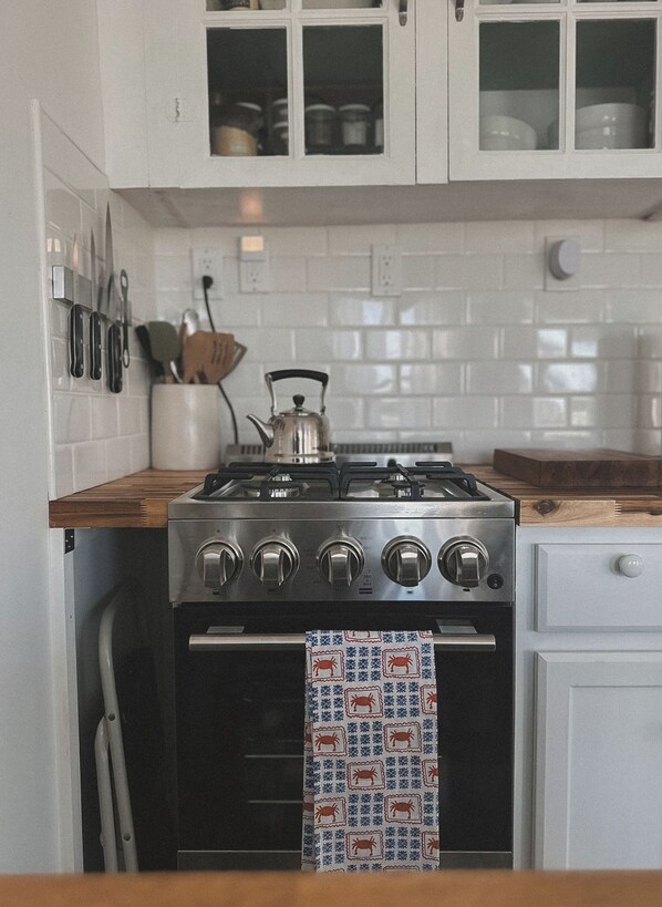 Una cocina con armarios blancos, una estufa de acero inoxidable y una toalla estampada colgada sobre el horno.