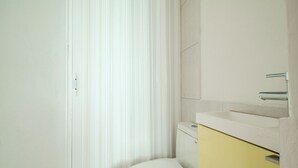 Un baño con inodoro blanco, un armario amarillo y lavamanos blanco.