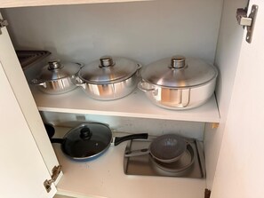 A kitchen cabinet with stainless steel pots and pans.