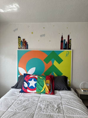 A bed with a colorful headboard, pillows with various designs, and a wall with a cityscape decal. - Family-Friendly Room, 2 Queens, Pool, Near Disney (Kissimmee)