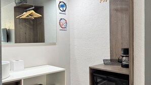 Ein modernes Badezimmer mit einem weißen Waschtisch, einem Spiegel, einem Handtuchhalter, einer Kaffeemaschine, einer Mikrowelle und einem Kühlschrank.