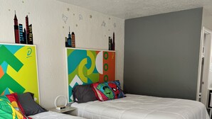 Ein Hotelzimmer mit zwei Betten, einer grauen Wand und einem Stadtbild-Wandgemälde.