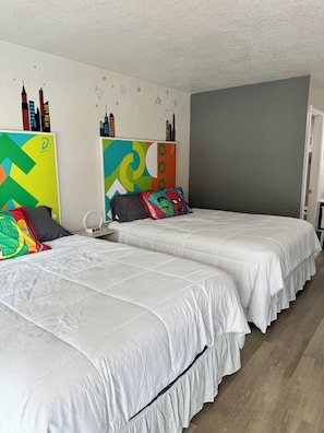A hotel room with two beds, a gray wall, and a cityscape mural. - Family-Friendly Room, 2 Queens, Pool, Near Disney (Kissimmee)