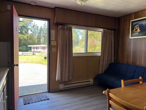 Una habitación con paredes de madera, una cama, una mesa y una puerta que da al exterior.