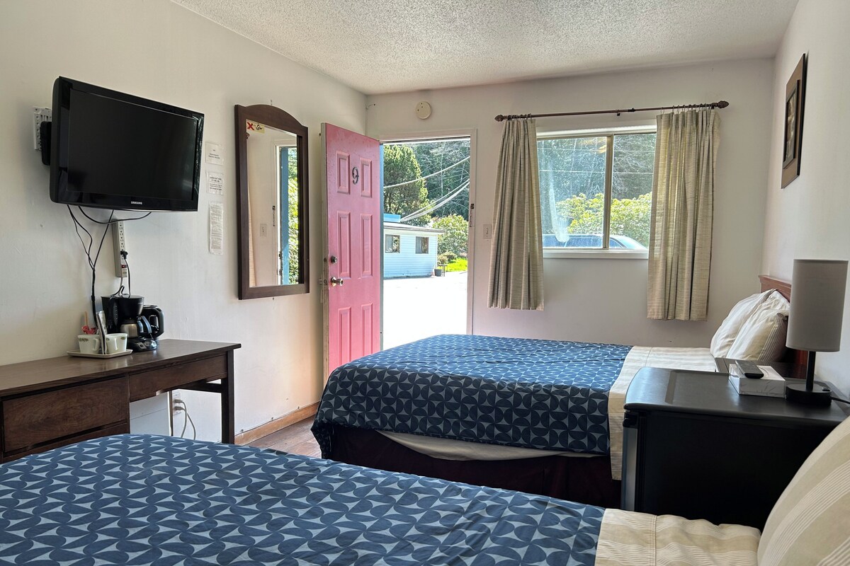 Habitación de hotel con dos camas, un escritorio con cafetera, televisión y ventana con cortinas.