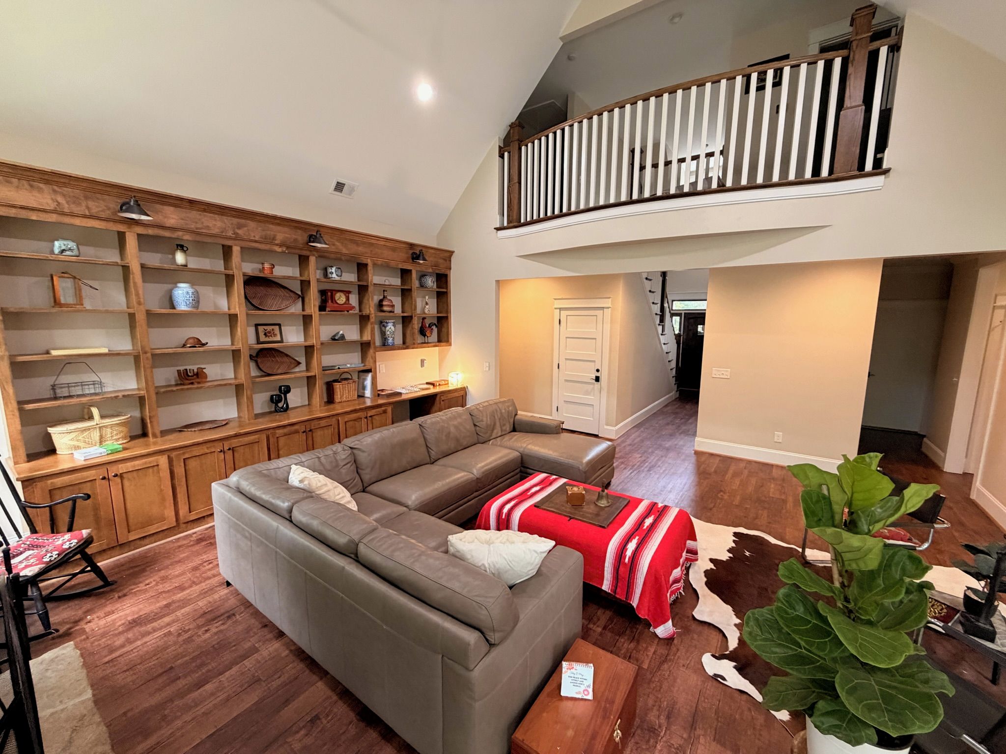 Amplia sala de estar con sofá seccional, estanterías de madera y una escalera que conduce a un nivel superior.