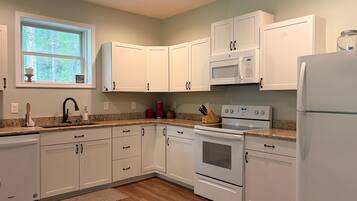 A kitchen with white cabinets, a microwave, a stove, and a refrigerator.