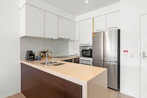 Une cuisine moderne dotée d’un îlot central, d’appareils électroménagers en acier inoxydable et de meubles de rangement blancs.