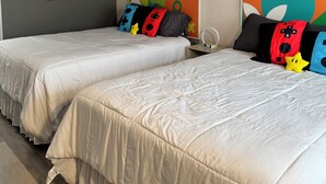 Ein Hotelzimmer mit zwei Betten, einer Wand mit Mario und Luigi Figuren und abstrakter Kunst.