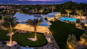 Un resort moderno con piscina, palmeras y vistas a las montañas.