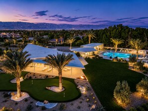 Ein modernes Resort mit Swimmingpool, Palmen und Blick auf Berge.
