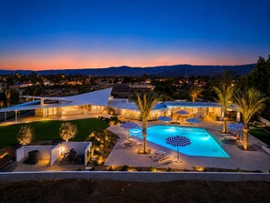 Ein Resort mit Swimmingpool, Liegestühlen und Palmen.