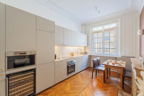 A modern kitchen with built-in appliances, a dining area with a table and chairs, and a large window providing natural light. - Le Charme Chavannes - Welkeys (Paris)