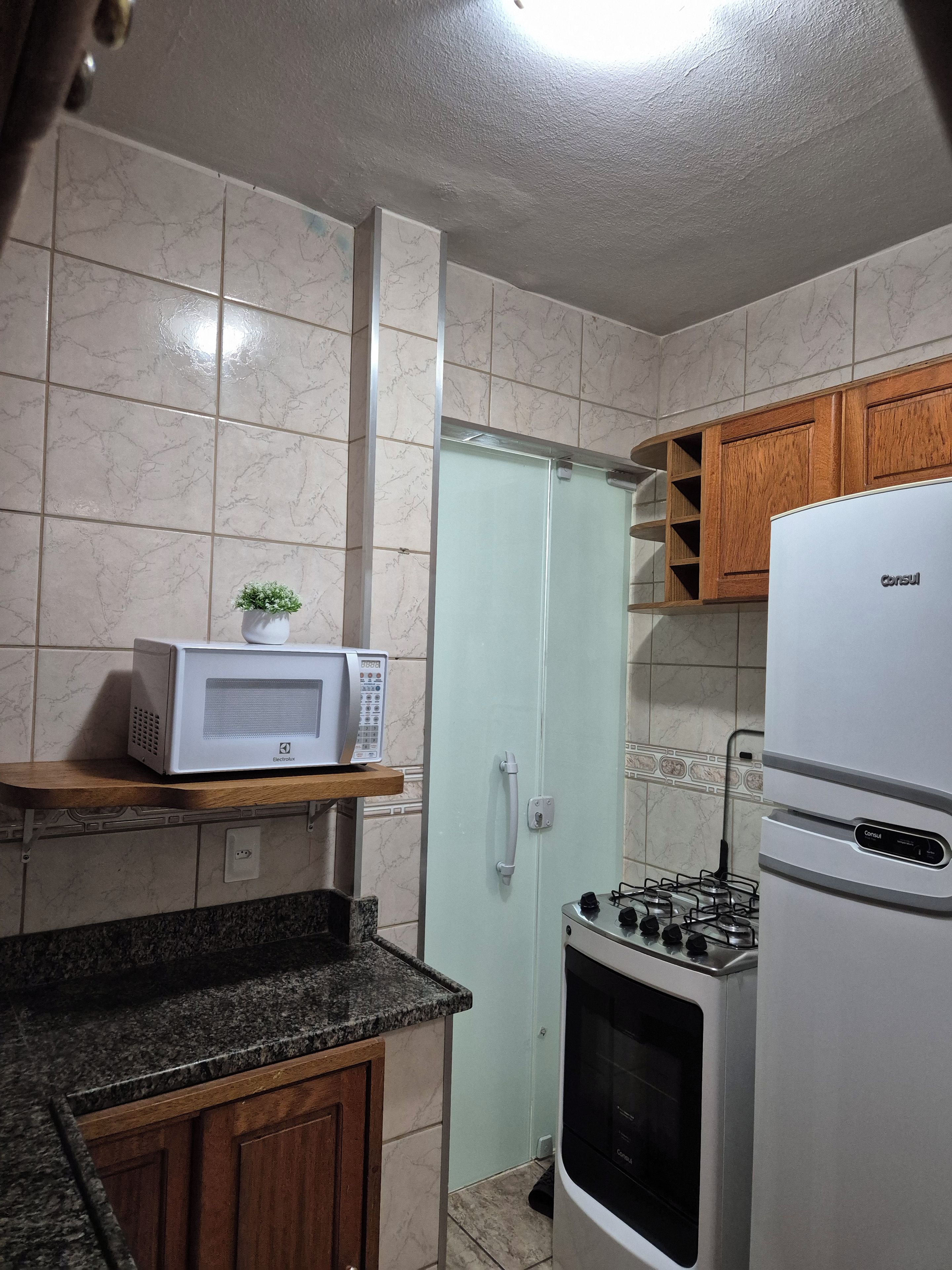 A compact kitchen with a microwave, stove, and cabinets.