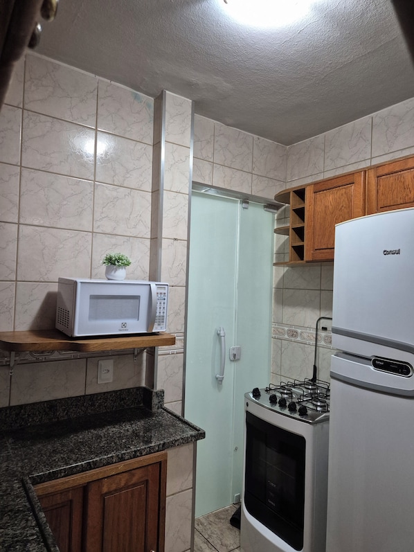 A compact kitchen with a microwave, stove, and cabinets.