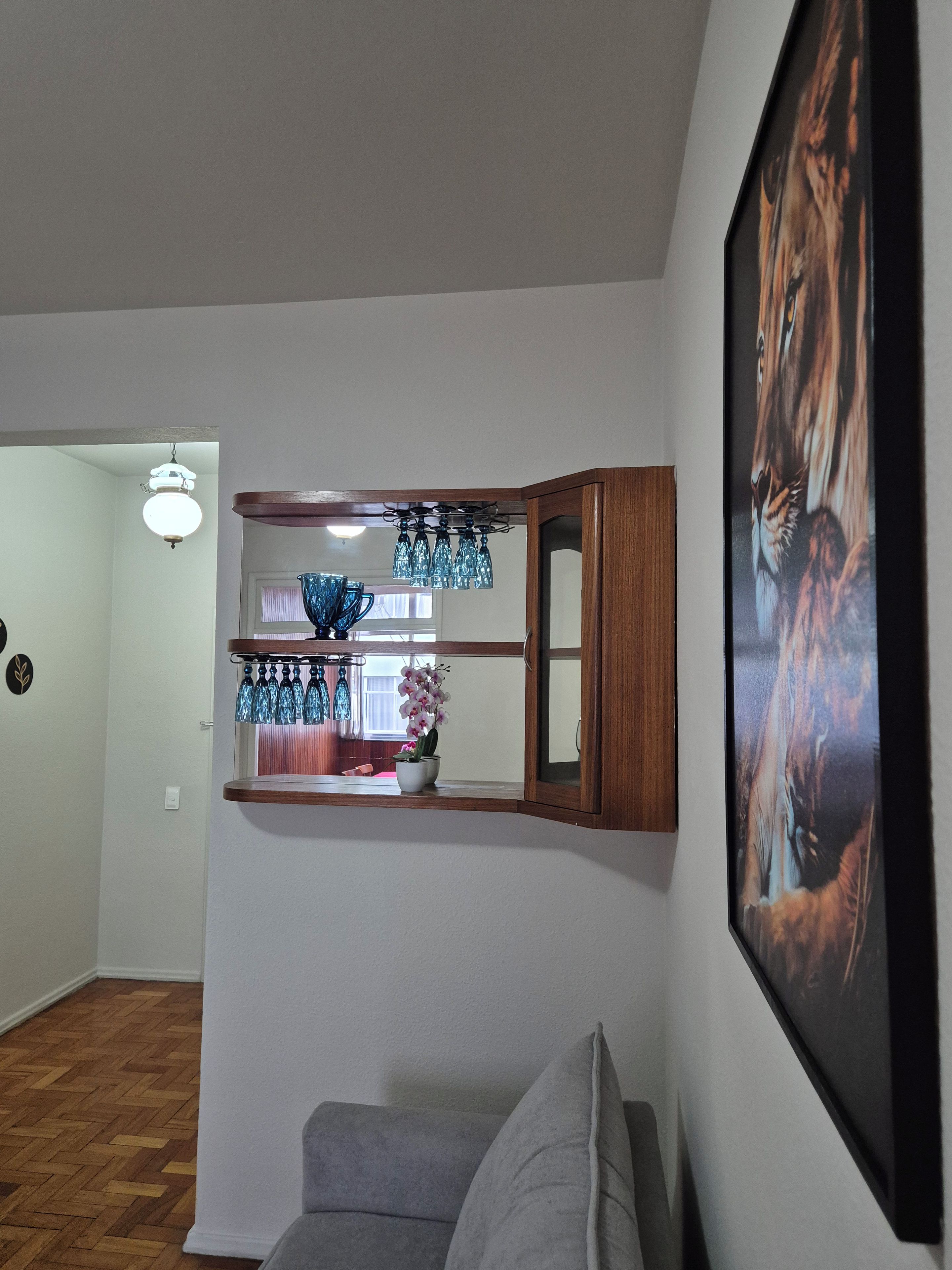 A living room with a gray sofa, a wooden cabinet with blue glassware, and a framed picture on the wall.