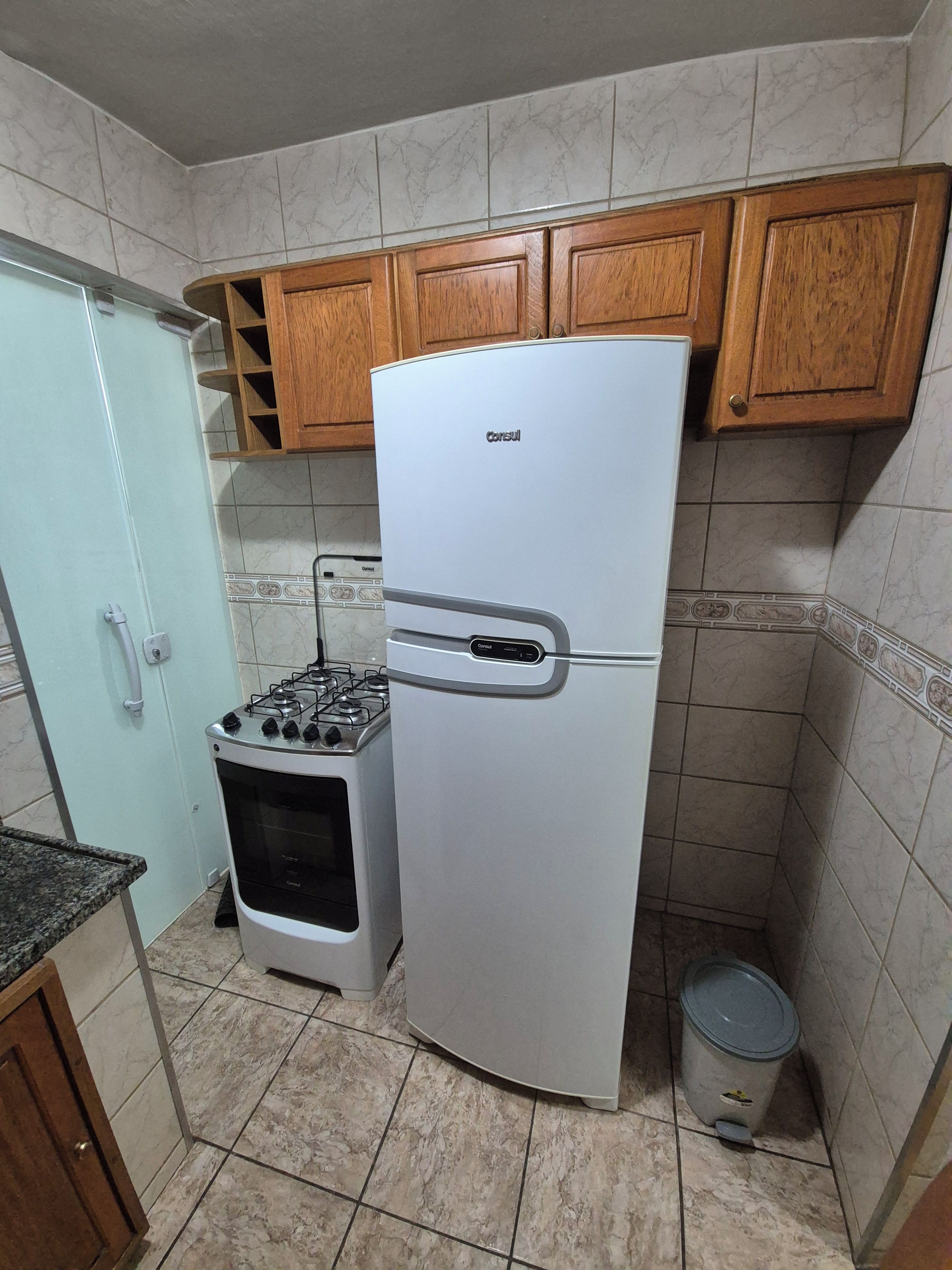 A kitchen with a white refrigerator, a stove, wooden cabinets, and a tiled backsplash.