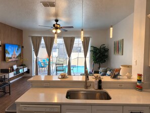 A modern kitchen with a central island, a built-in dishwasher, and a view of a pool. - Private 3B 3B- Pool Townhome Near Disney - Family Getaway (Kissimmee)