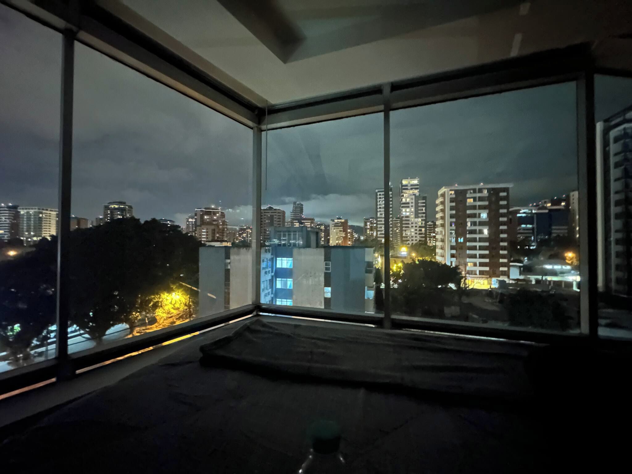 A room with large windows overlooking a cityscape at night.