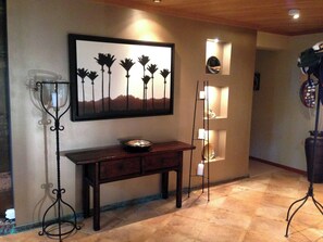 A hallway with a wooden console table, a framed artwork, and a floor lamp.