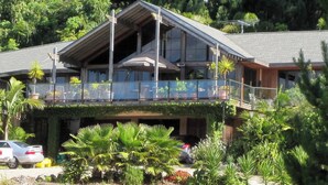 A two-story building with a balcony, surrounded by lush greenery. - O'Grady Lodge - The Whole Wing (Wainui)