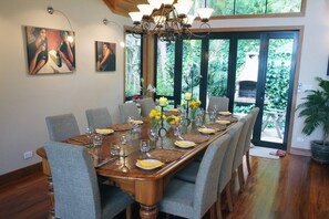 A dining room with a large wooden table set for six, surrounded by grey upholstered chairs.