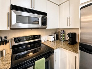 A modern kitchen with stainless steel appliances, including a microwave, stove, and refrigerator. - South Core Suites (Toronto)