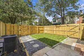 A backyard with a wooden fence, a lawn, and a gravel path.