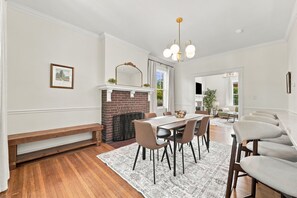 A dining area with a brick fireplace, a wooden bench, and a dining table with chairs.