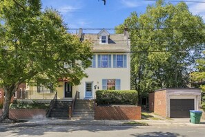 A two-story residential building with a front entrance, a small porch, and a garage.