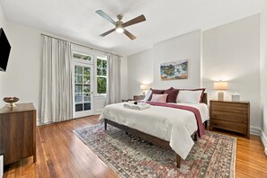 A bedroom with a bed, bedside tables, a ceiling fan, and a window with curtains.