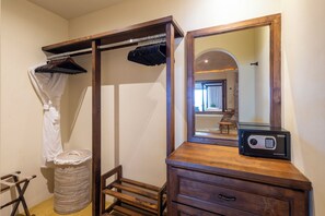 Ein Schlafzimmer mit einem hölzernen Kleiderschrank, einem Spiegel, einer Duschvorhang und einer kleinen Mülltonne.