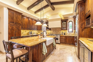 A kitchen with wooden cabinets, a granite countertop, a central island, and a hanging light fixture. - Casa Lomboy - Cabo del Sol | 6 Bed, 6.5 Bath (Cabo San Lucas)