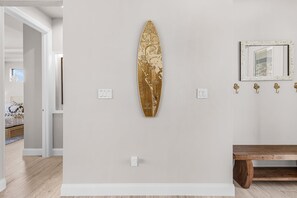 Ein Zimmer mit einem Surfbrett-Kunstwerk, einem Spiegel und einer Holzbank.