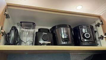 Et køkkenskab med indbygget hylde, der indeholder forskellige apparater, herunder en blender, kaffemaskine og en rislampe.