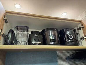 Ein Küchenschrank mit eingebautem Regal, das verschiedene Geräte wie einen Mixer, eine Kaffeemaschine und einen Reiskocher beherbergt.